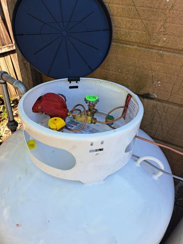 Open propane tank with visible regulator and valve components.