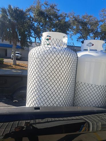 Two large white propane tanks in the back of a truck on a sunny day.