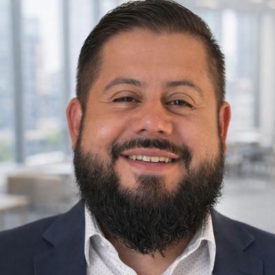 Smiling man with beard in a formal suit indoors.