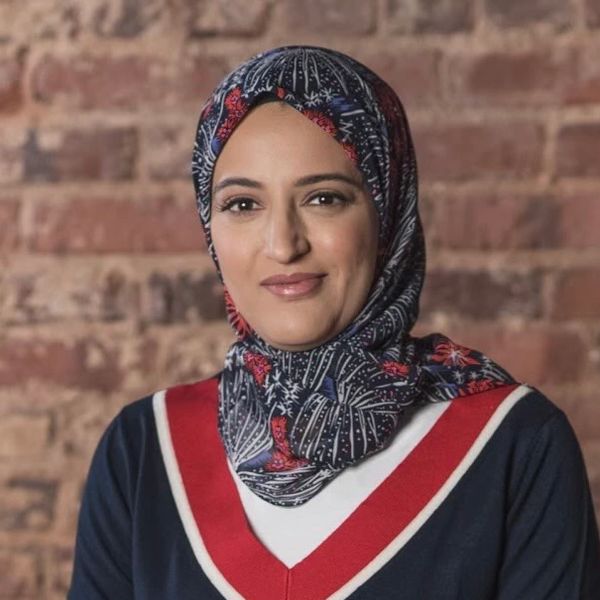 Woman wearing a floral hijab and navy blue outfit.