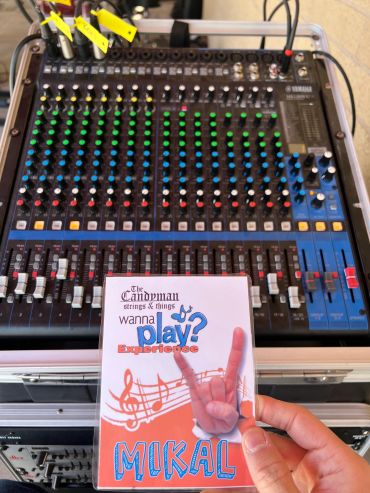 A hand holding a laminated card in front of a Yamaha audio mixer.