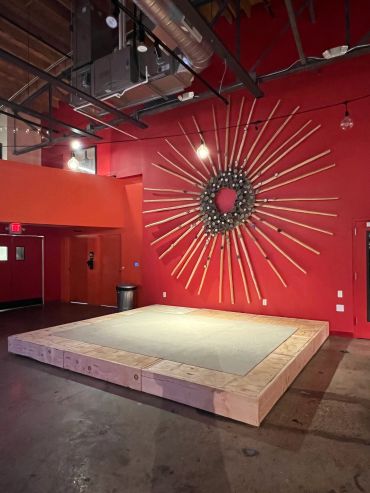 Empty stage with sunburst wall art in a red-walled room.