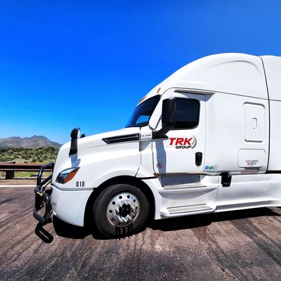 White semi truck parked on the side of a road under a clear blue sky.