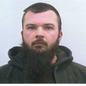 Portrait of a man with a dark beard and hoodie.