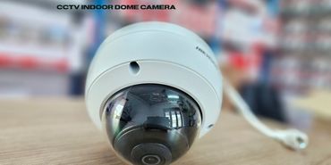 Close-up of a CCTV indoor dome camera on a wooden surface.