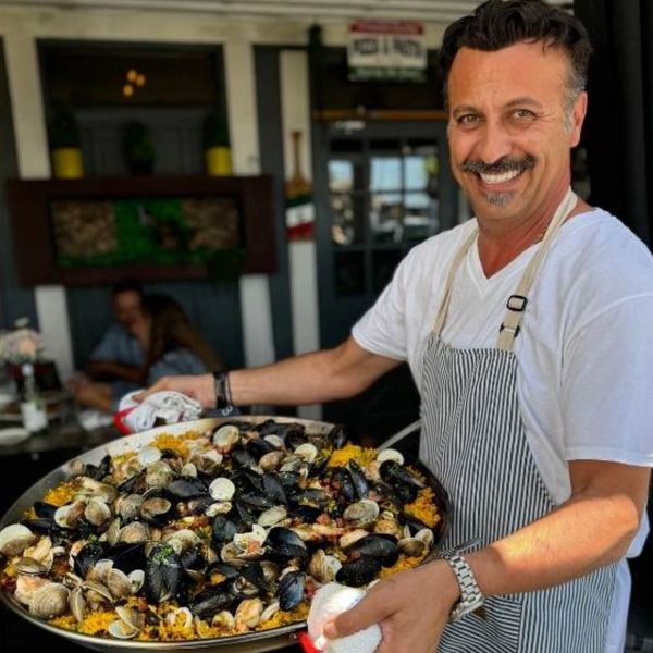 Chef and Owner Dino Ferraro holding large seafood paella.