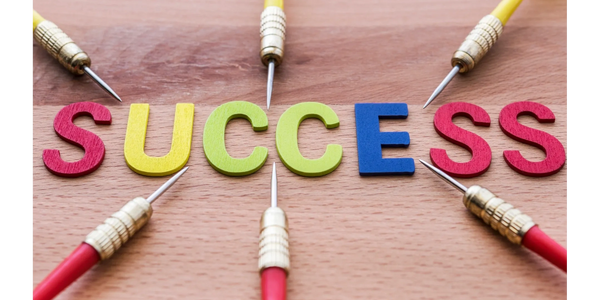 Yellow and red darts on a table pointing to the word success