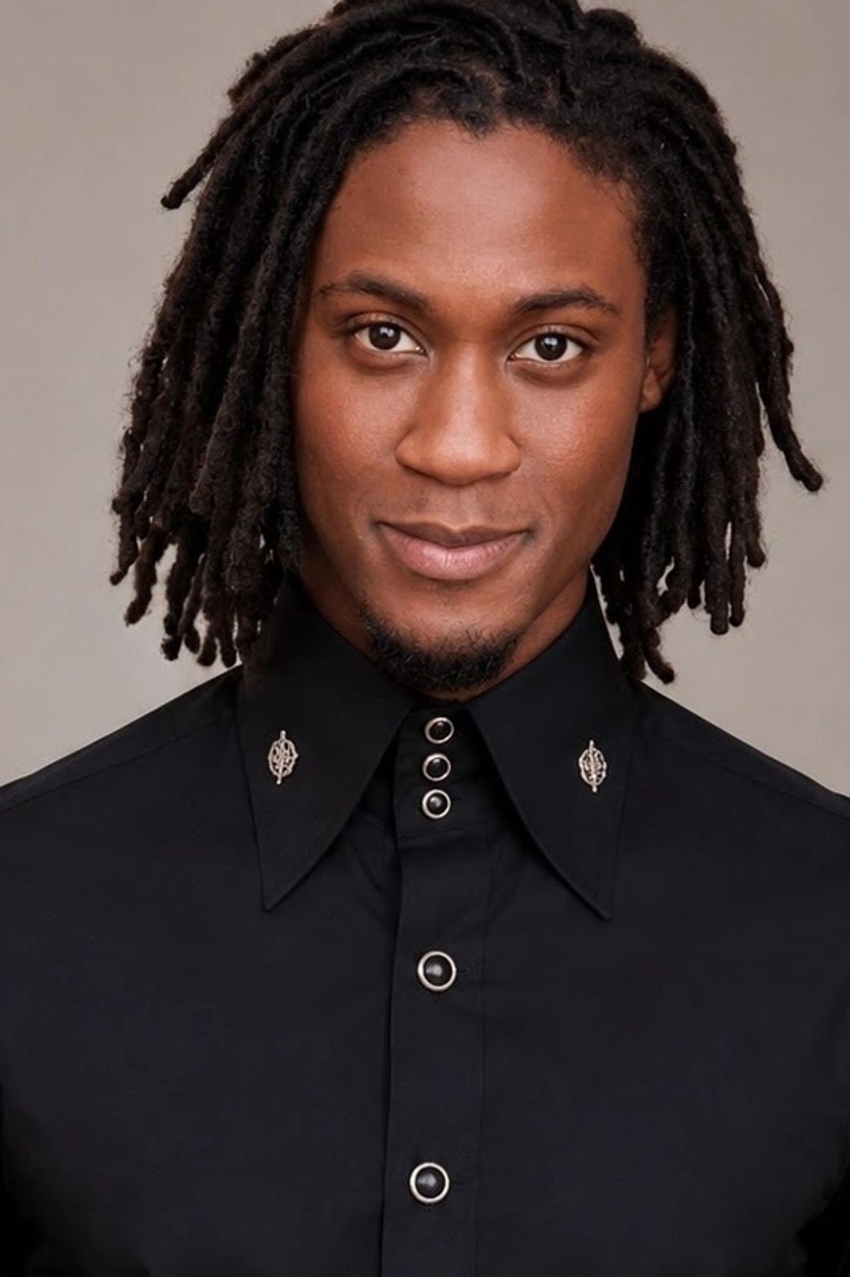 Close-up portrait of a smiling man with dreadlocks.