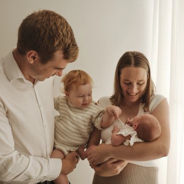 Happy family with newborn and toddler sharing a tender moment.