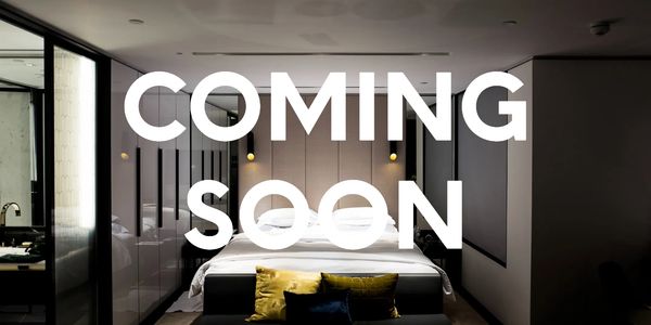 A bed in an expensive hotel room with the words 'coming soon' across the image