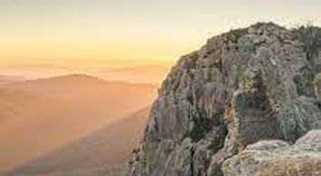 A large rocky mountain with a sunset in the background