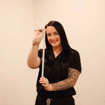 Smiling woman holding a measuring tape.