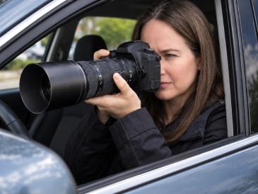 Woman photographing from inside a car with a telephoto lens.