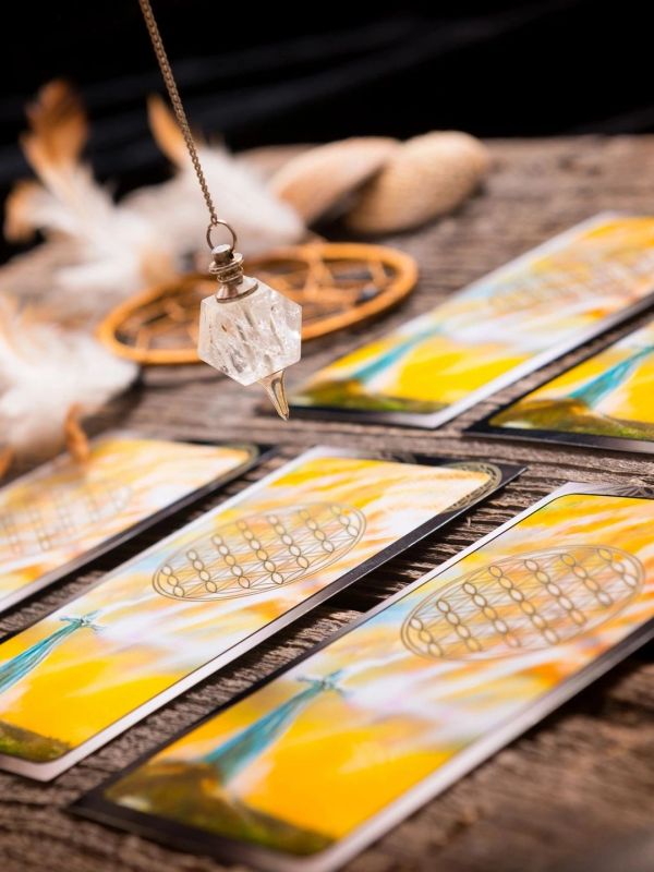 Pendulum suspended over tarot cards on wooden surface.