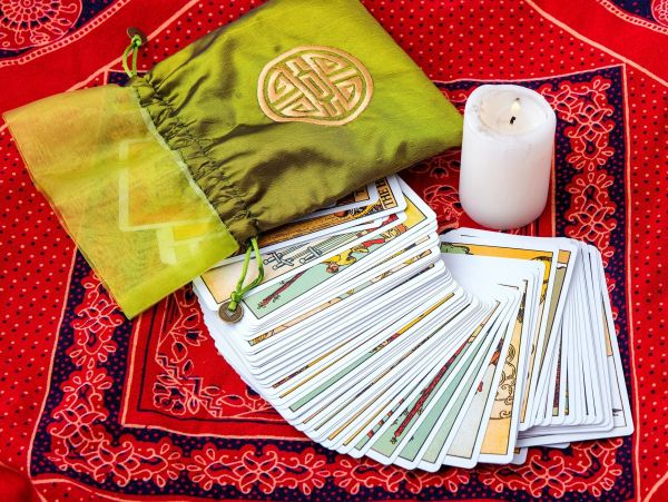 Tarot cards spread out with a candle and green pouch.