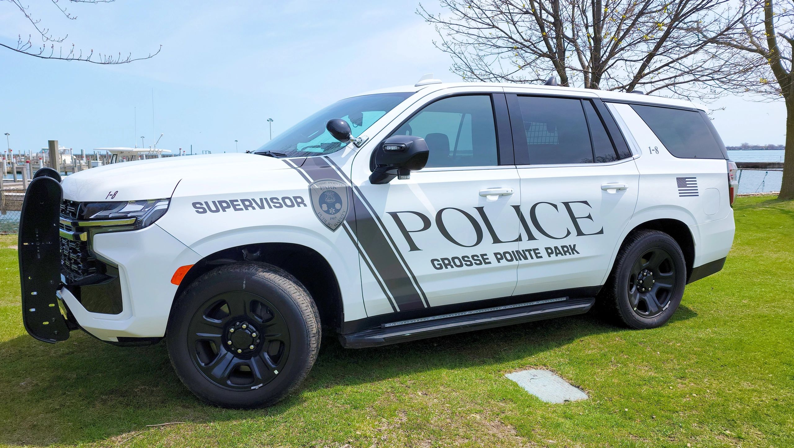 White police SUV with 'Supervisor' and 'Grosse Pointe Park' markings parked on grass.