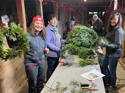 Five people in a barn creating Christmas Wreaths at the River Ridge Lodge Christmas Wreath Workshop