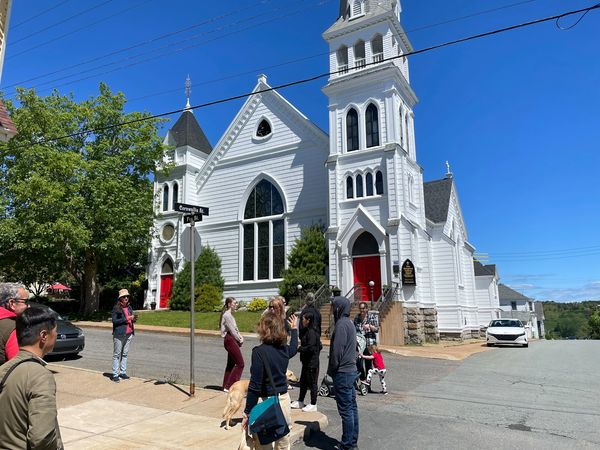 Group of people in front of a white church in Lunenburg taking part in a Lunenburg Walking Tour