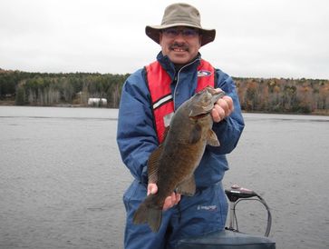 Fishing Guide Peter Lavender holding a big fish in front of a lake on Nova Scotia South Shore