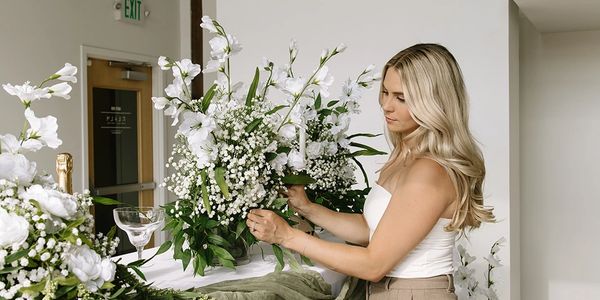 Woman arranging white flowers indoors.