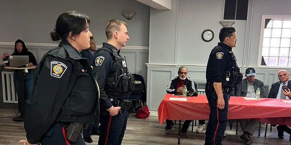 Police officers standing in a meeting room with seated attendees.