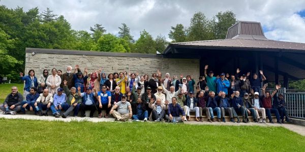 Large group photo outdoors in front of a building on a cloudy day.