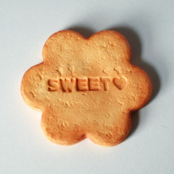 Flower-shaped cookie with the word 'SWEET' and a heart imprinted.
