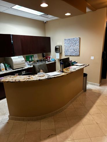 Reception area with curved granite countertop and office equipment.