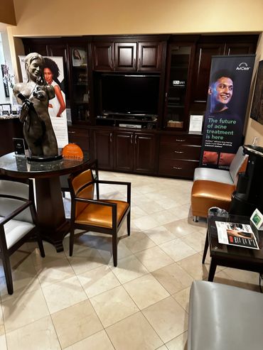 A waiting area with a statue, chairs, and acne treatment posters.