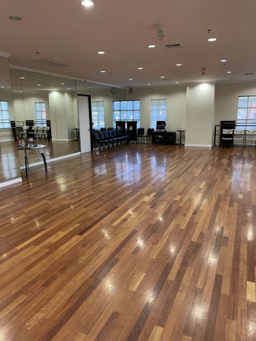 Spacious dance studio with wooden floors and mirrored wall.