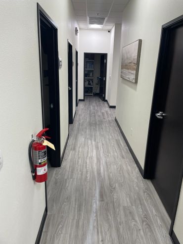 A clean hallway with black doors and a fire extinguisher on the wall.