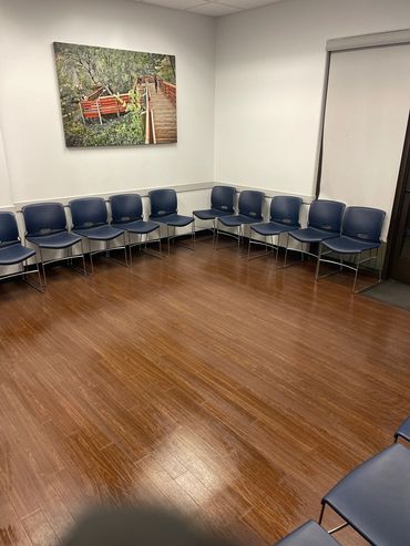Empty waiting room with blue chairs and wooden flooring.