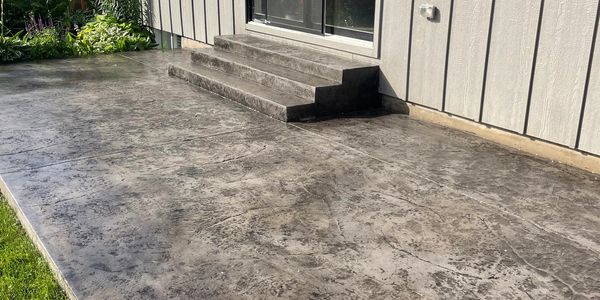 Stamped concrete patio with stairs leading to sliding glass doors.
