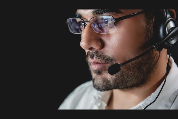 Close-up of a man wearing glasses and a headset, focused on work.