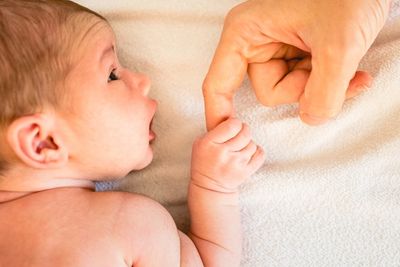 A newborn grasps its mother's finger.