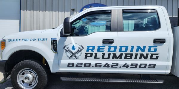 White plumbing truck with Redding Plumbing logo and contact number.