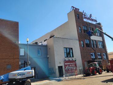 Building with hospitality sign and construction equipment under a clear sky.