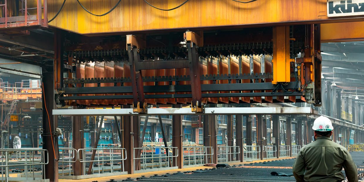Industrial worker inspecting machinery in a large factory.