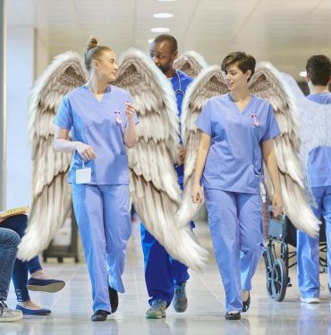 Healthcare workers with angel wings walking in a hospital hallway.