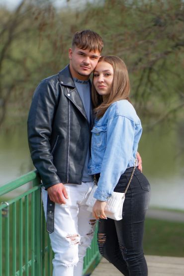 Young couple posing closely on a green bridge outdoors.