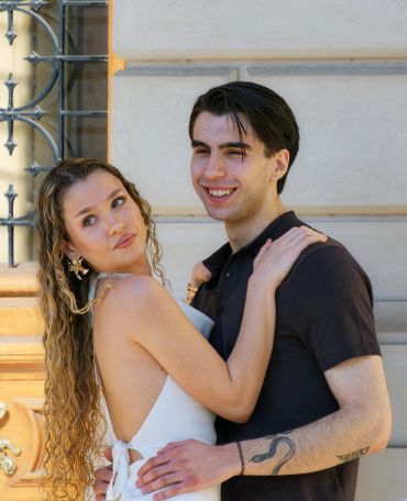 Young couple embraces outside on a sunny day, smiling and affectionate.
