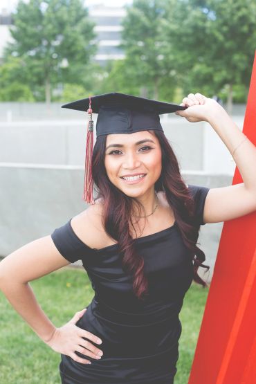 Smiling graduate in cap and gown outdoors.