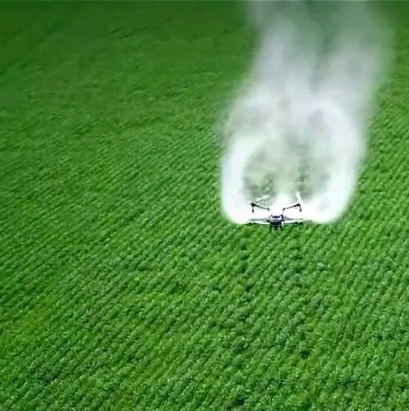 Drone spraying crops over a green field.