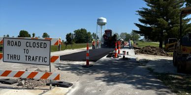 Road closed sign with ongoing road construction and machinery.