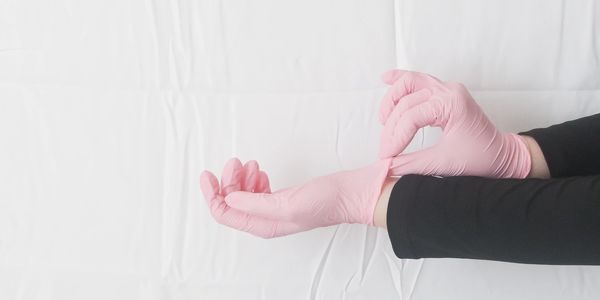 Person wearing pink gloves against a white background.
