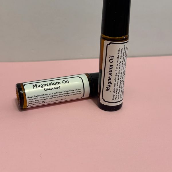 Two small bottles of unscented magnesium oil on a pink surface.