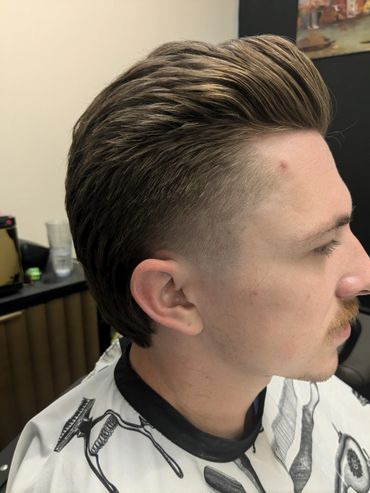 Side profile of a man with a styled haircut and mustache.