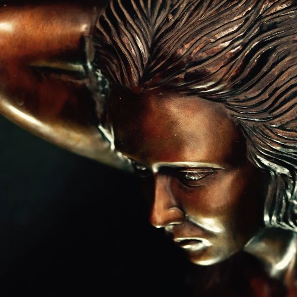 Escultura de bronce mostrando un rostro pensativo.
