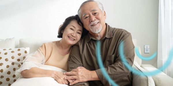 Elderly couple smiling and embracing on a cozy couch.