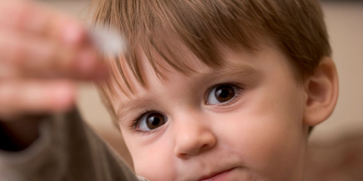 A toddler holding out a sticker as if to give it to the viewer